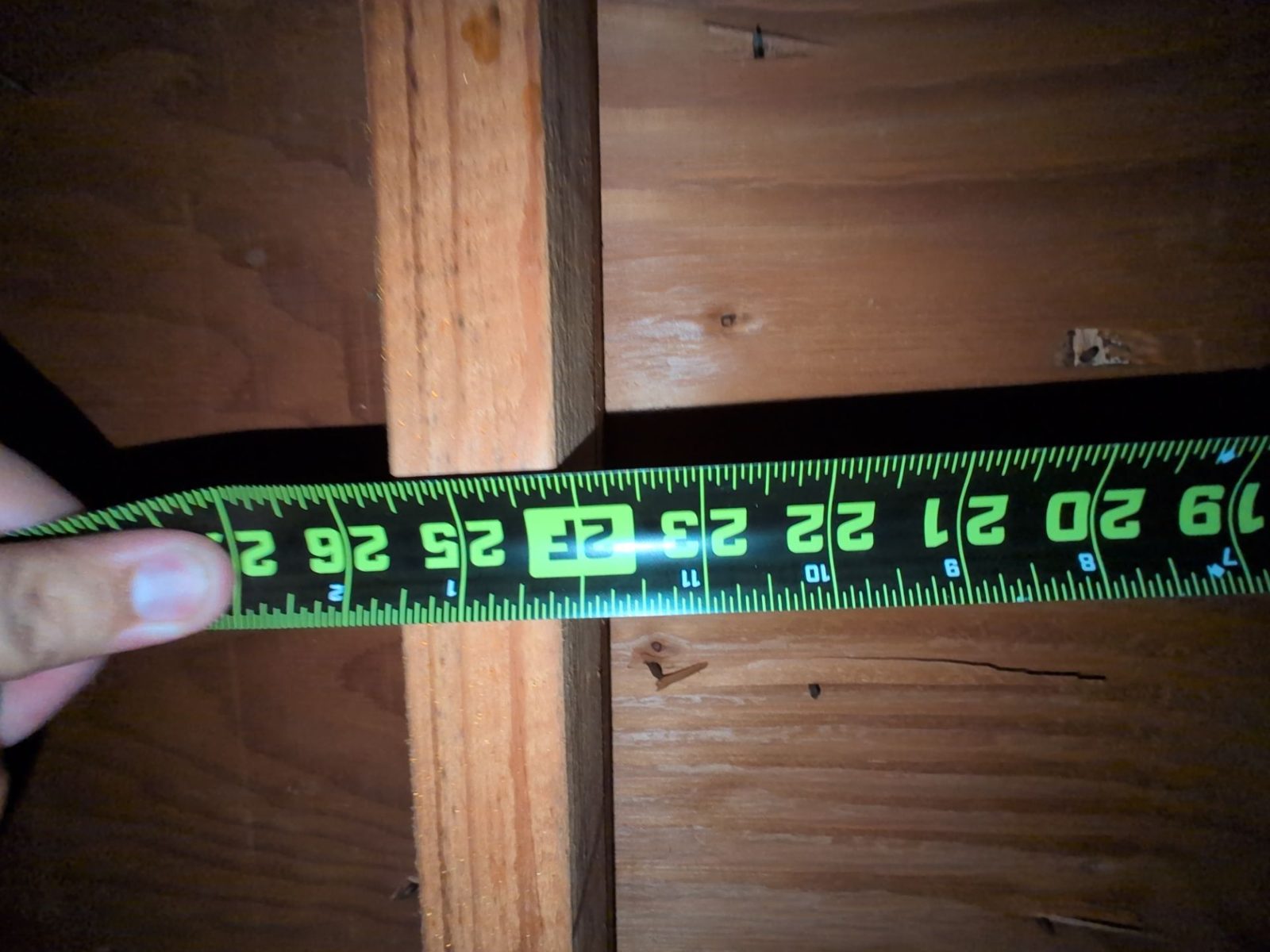 Tape measure across a rafter bay under roof sheathing