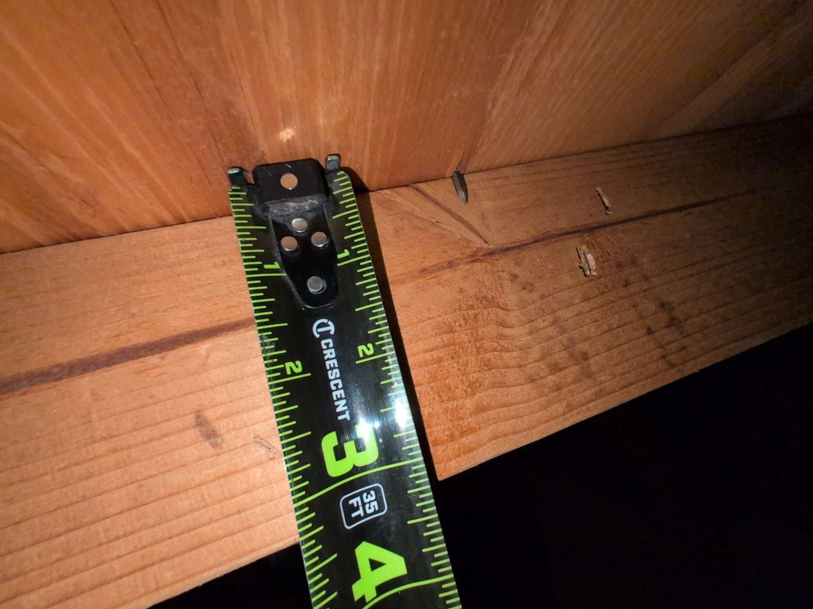 Tape measure reading the depth of an attic rafter