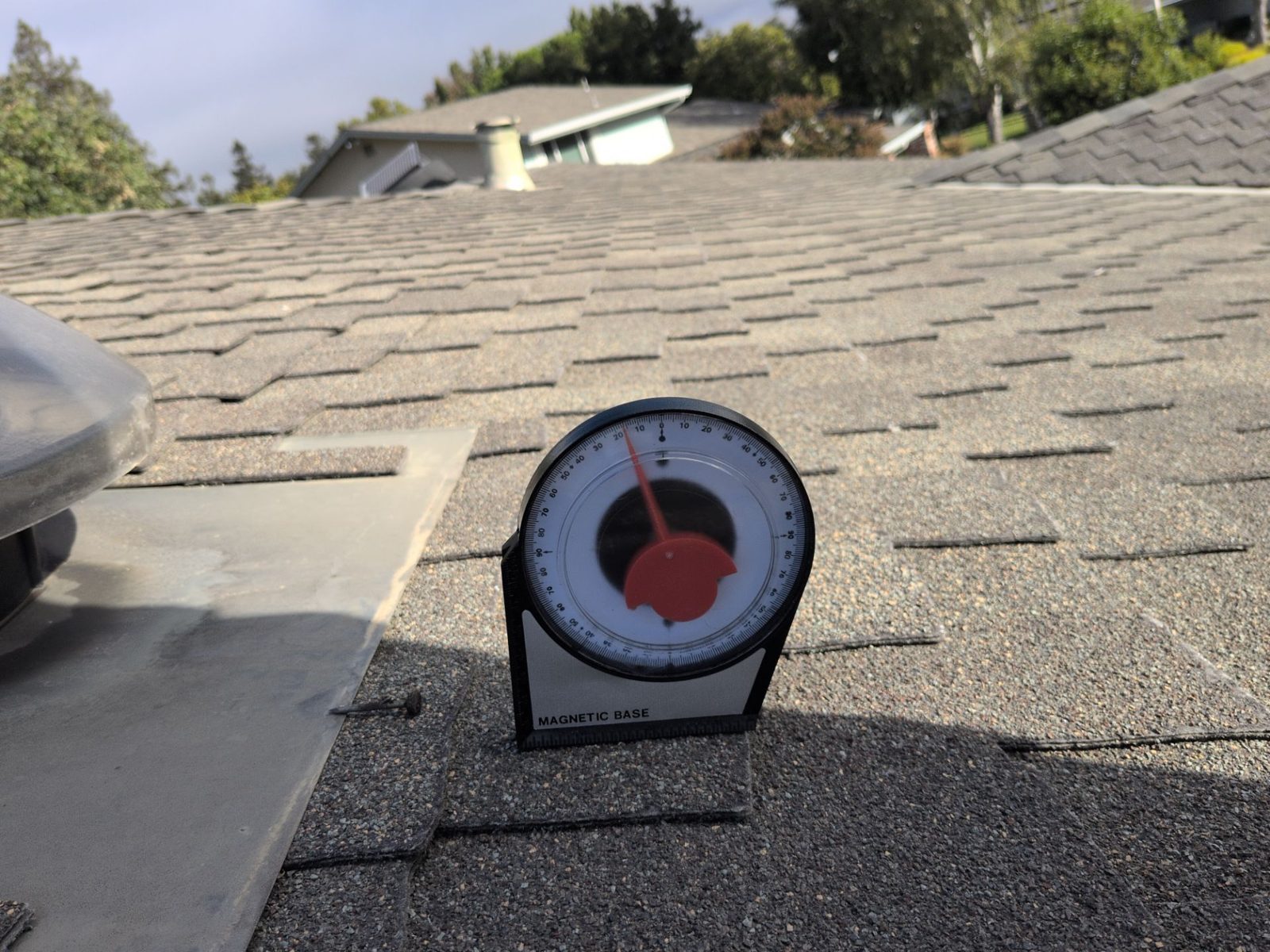 Pitch gauge on a shingle roof next to a roof vent